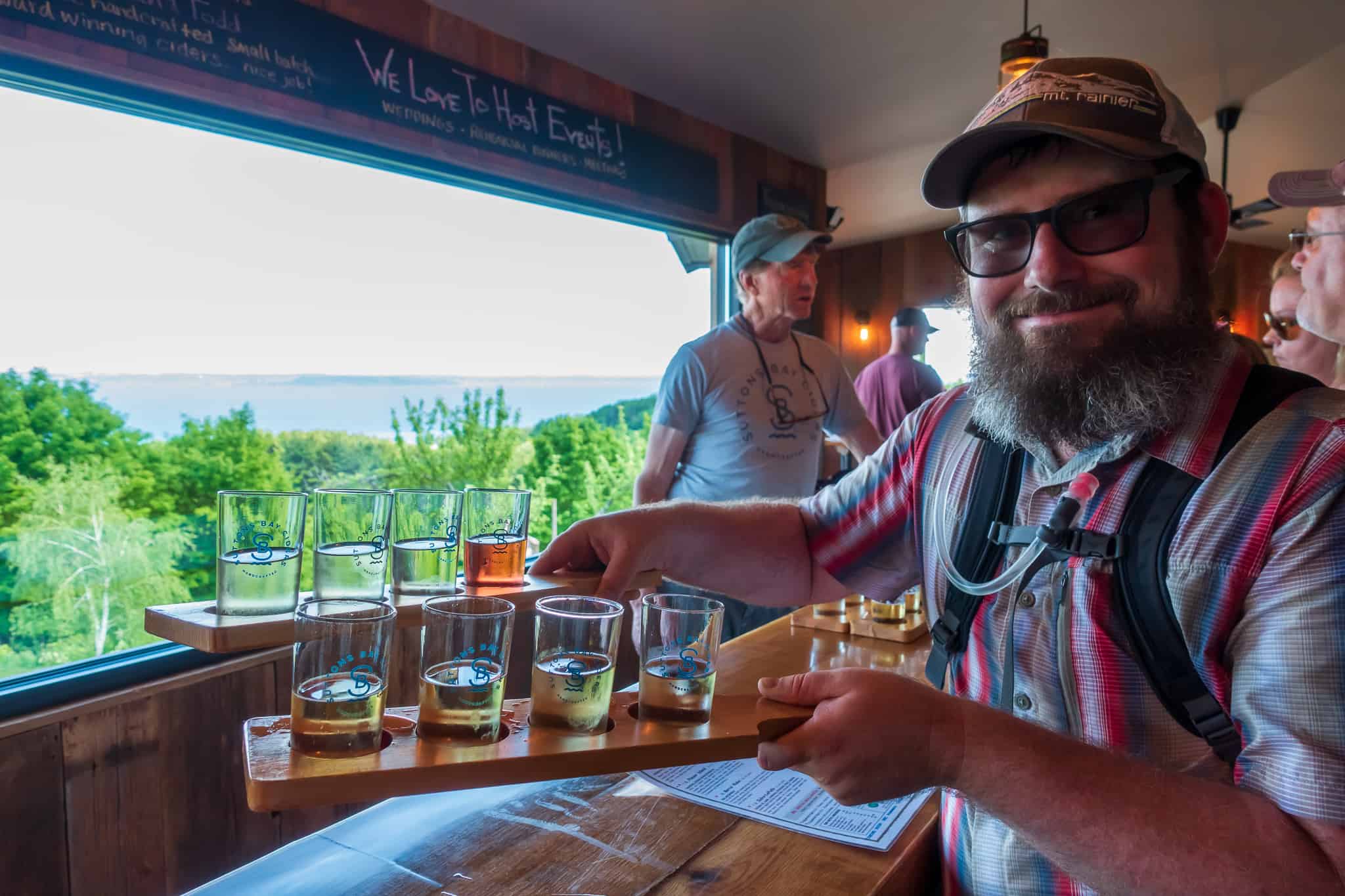 Barrett holding a cider flight at Suttons Bay Ciders on the Traverse City area DIY bike-n-ride tour